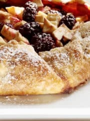 A rustic tart of apples and berries is lightly dusted with powdered sugar.
