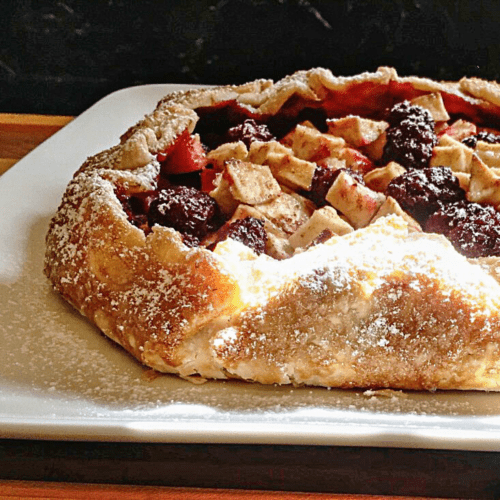 Close up view of a rustic fruit tart on a plate.