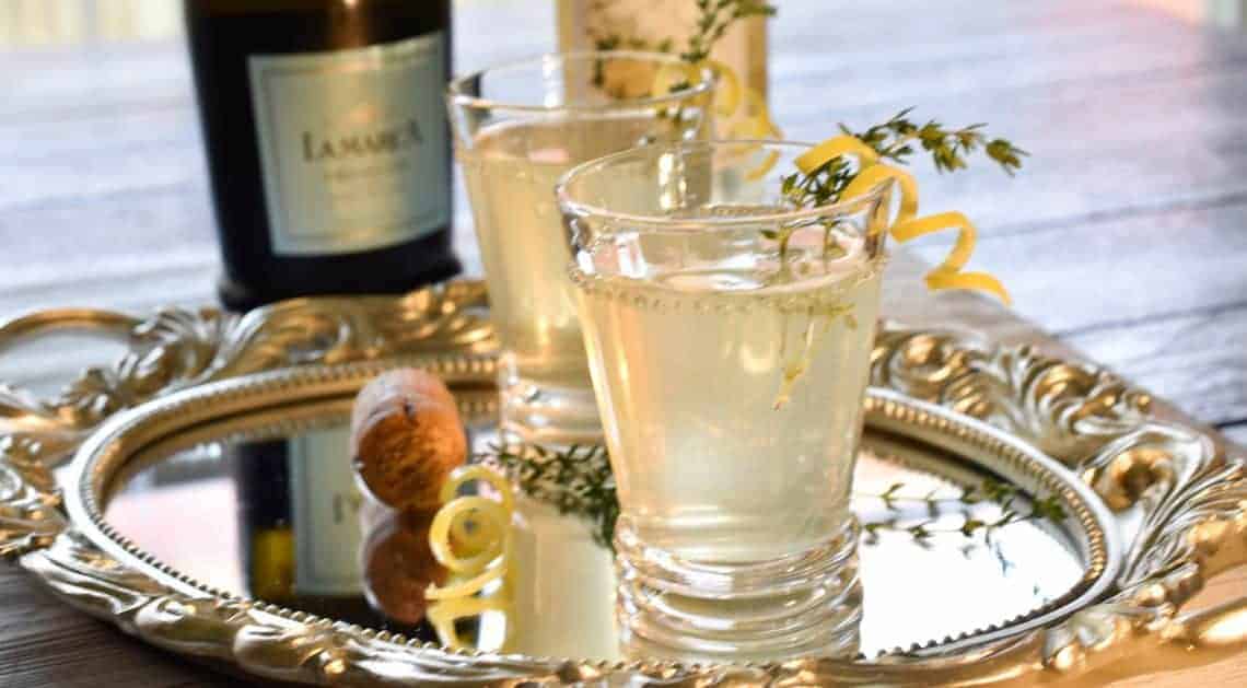 Elderflower and Lemon Mimosas , garnished with lemon twists and herbs on a fancy tray