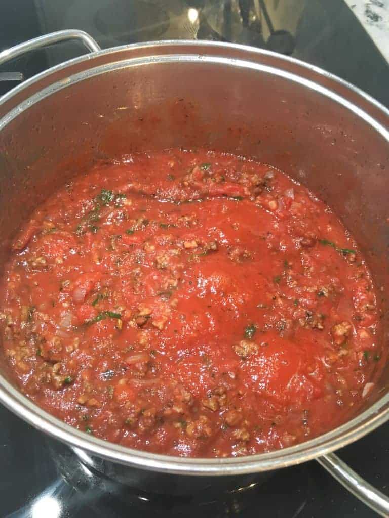 The finished sauce after cooking for 2 hours. The sauce is still bright red with chucks of meat and bits of basil clearly visible.