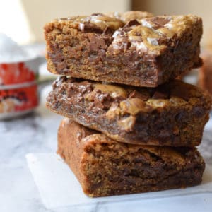 gooey toffee blondies are stacked 3 high on a square of parchment paper