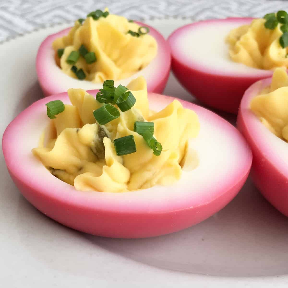 Pink tinted eggs filled with deviled yolks and sprinkled with chopped fresh green chives.