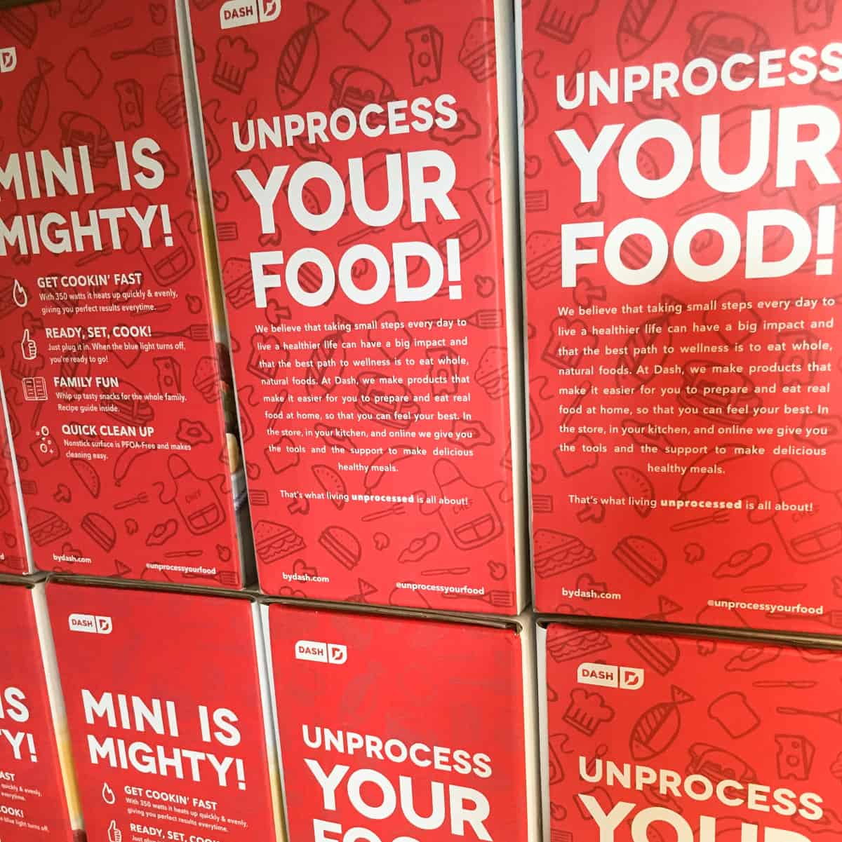 Stacked boxes of Dash Mini Waffle Makers. The words "Unprocess Your Food!" are repeated on the boxes.