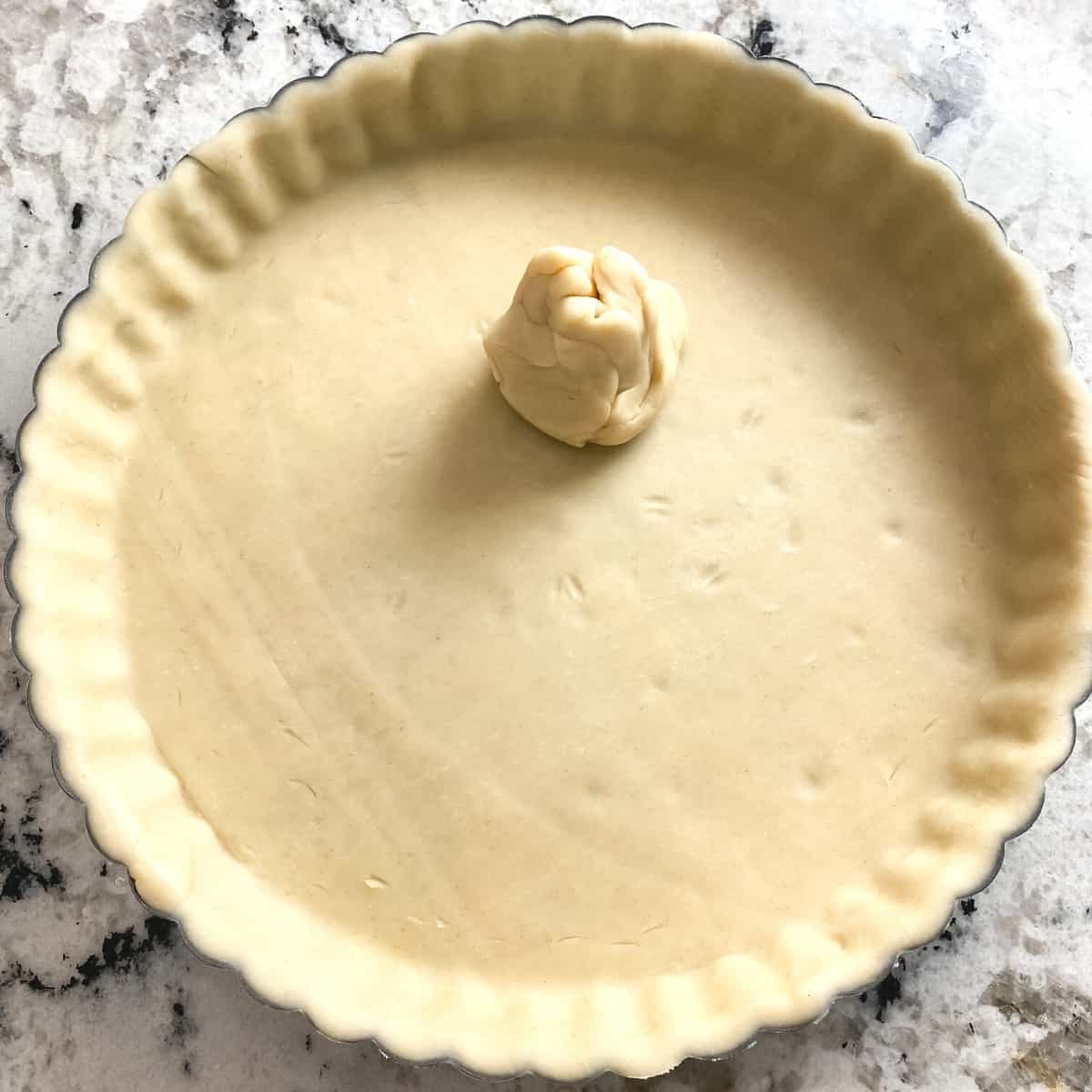 Pie crust is eased and pressed into a tart pan.