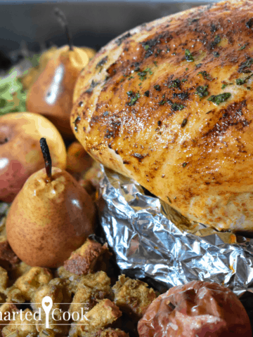 Square image of a roasted turkey breast surrounded with side dishes in it's roasting pan.