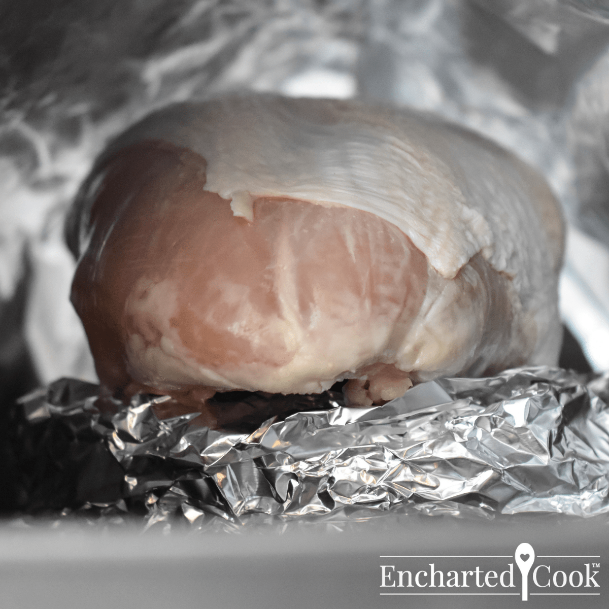 A turkey breast is tented with aluminum foil.  The foil does not touch the turkey.