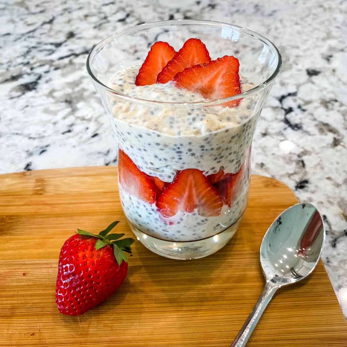 Refrigerator oats are layered with sliced strawberries in a clear glass.