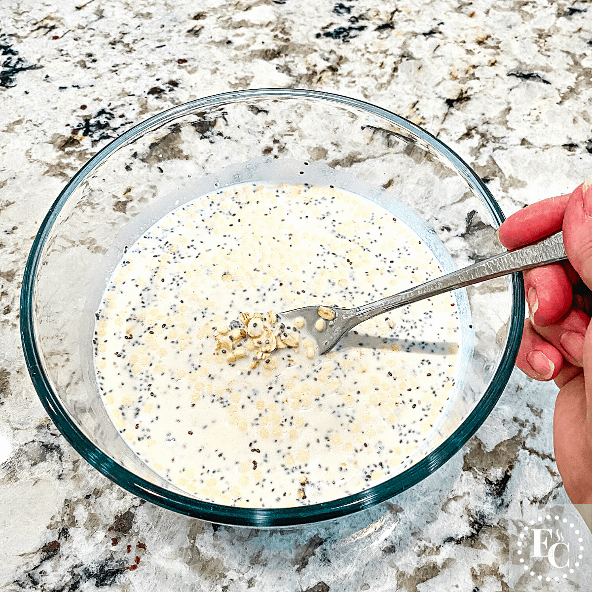In a glass bowl, mixing the ingredients for overnight oats with a fork.