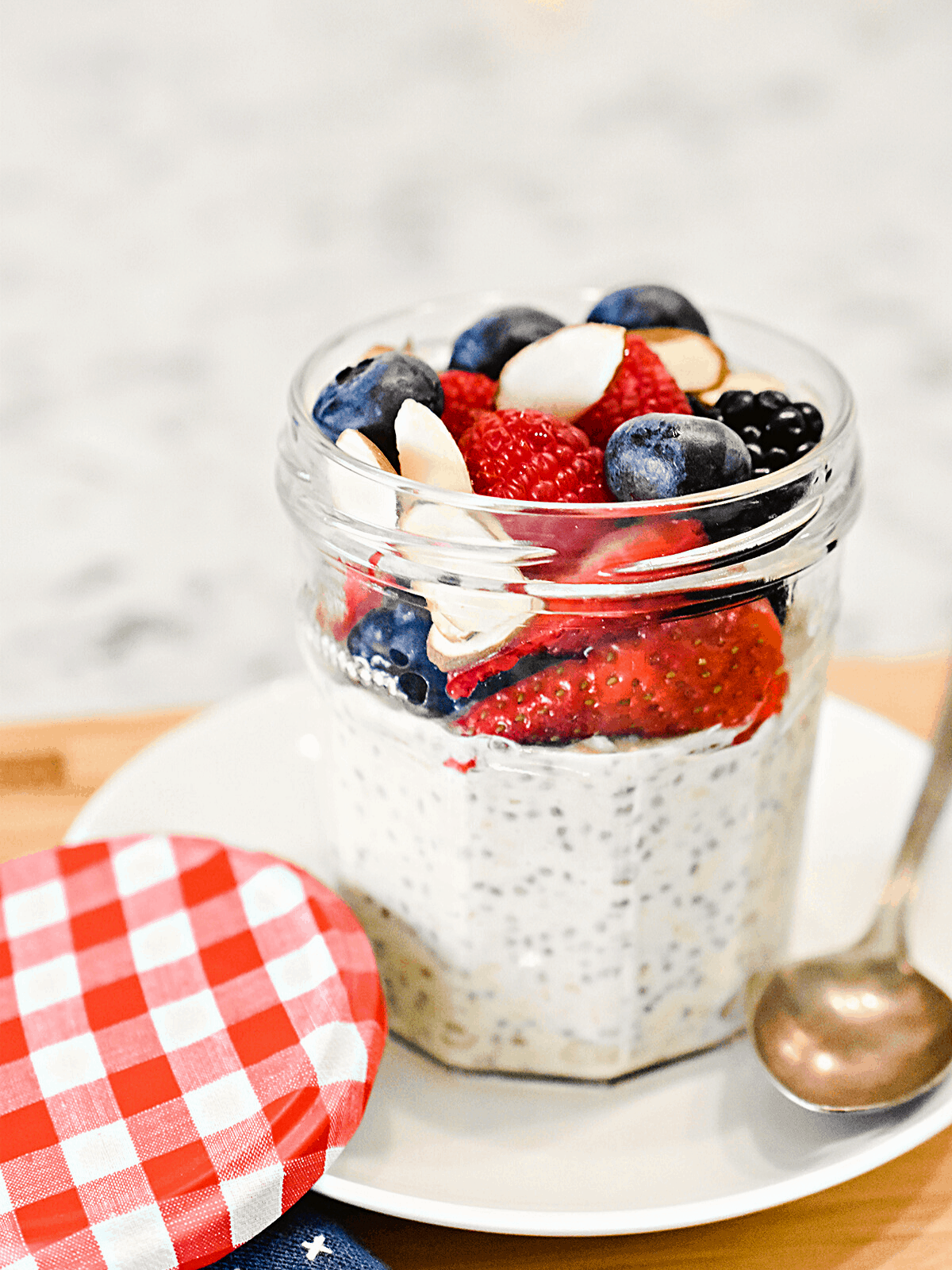 Overnight oats in a glass jar, topped with mixed berries and sliced almonds.