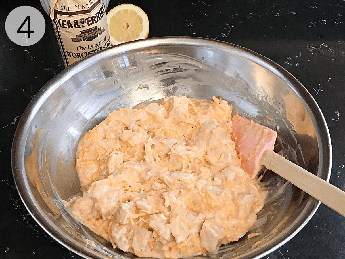 A large stainless steel mixing bowl contains chopped leftover cooked turkey combined with turkey divan sauce ingredients.