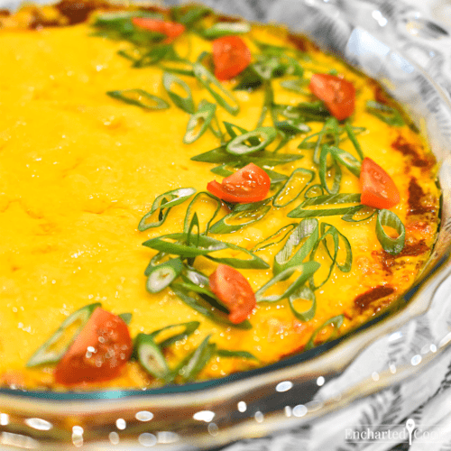 Layered dip is hot from the oven and garnished with sliced green onions and cherry tomatoes.