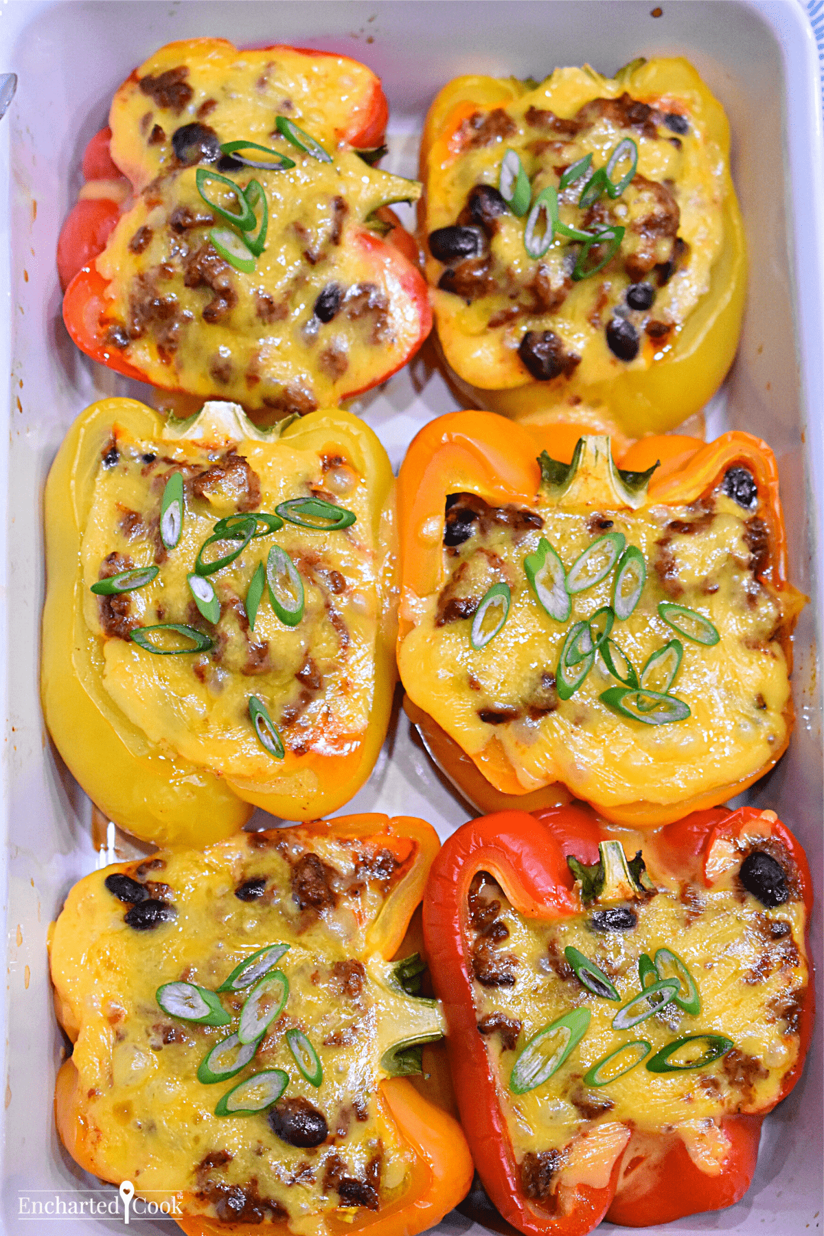 Halved stuffed bell peppers in a white baking dish.