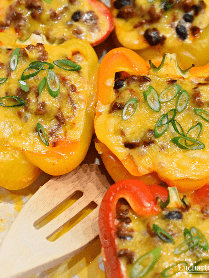 Halved bell peppers stuffed with meat, vegetables, and cheese in a white baking dish.