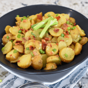 Sliced potatoes, green onions, and bacon bits in a black bowl.