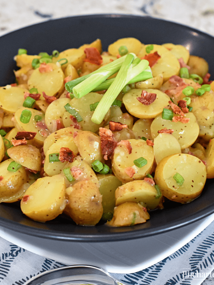 Sliced potatoes, green onions, and bacon bits in a black bowl.