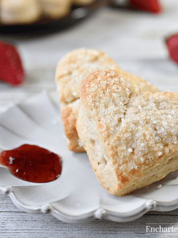 Two scones on a ruffled plate with a dab of strawberry jam.