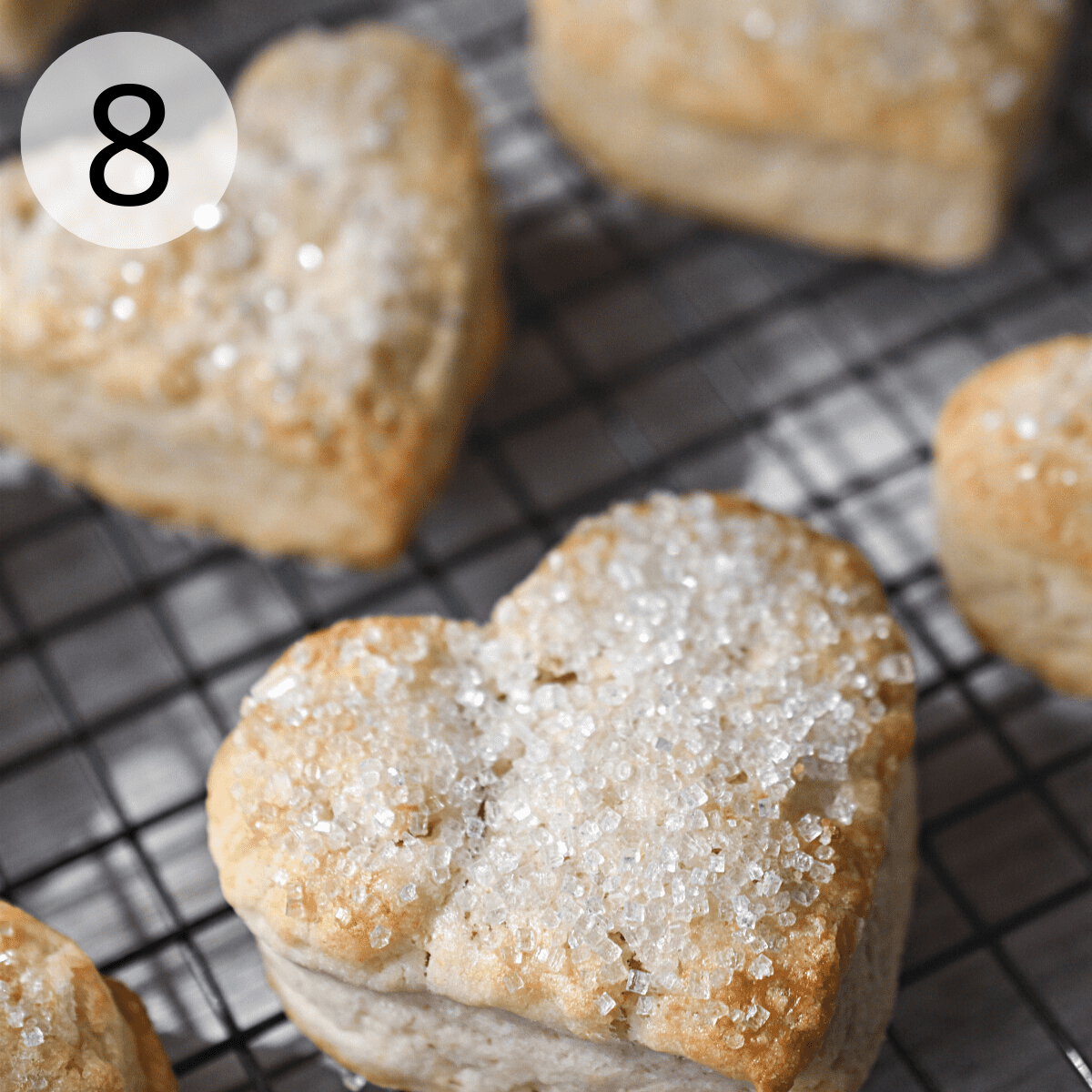 Baked heart shaped scones on a black wire cooling rack.