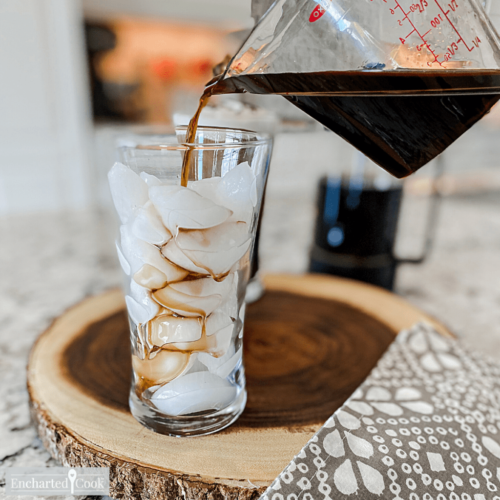 Cold coffee and brown sugar simple syrup is poured over ice in a glass.