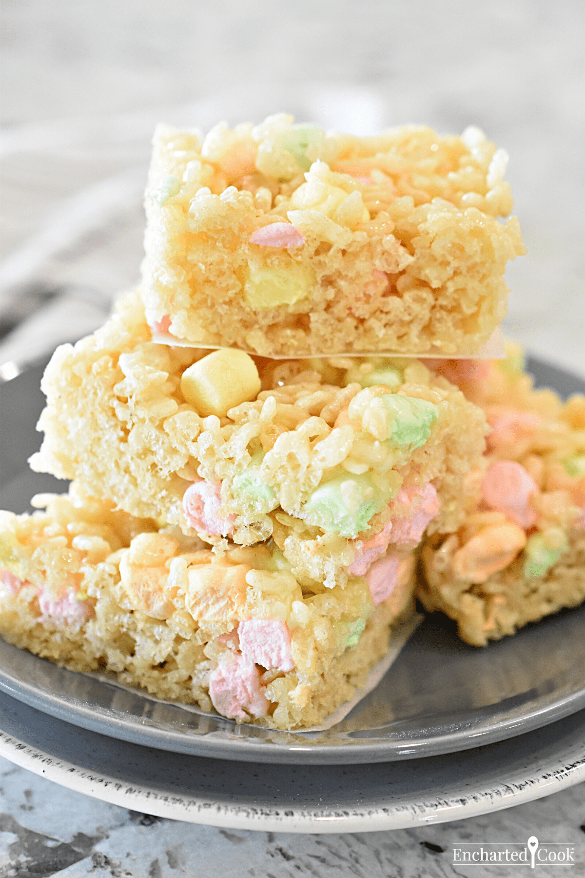 Squares of krispie treats are stacked on a grey plate.