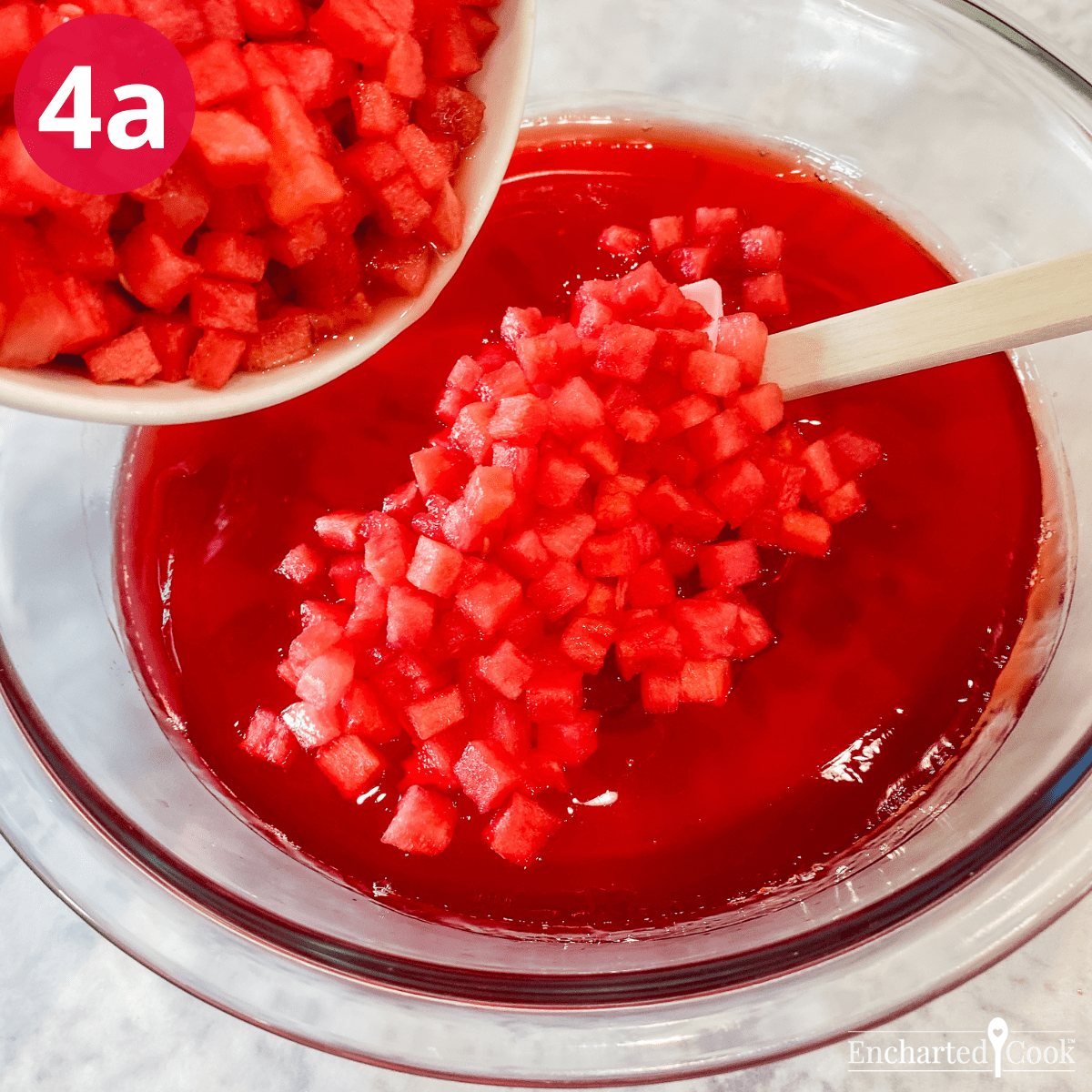 Adding tiny cubes of watermelon to soft set strawberry Jell-O.