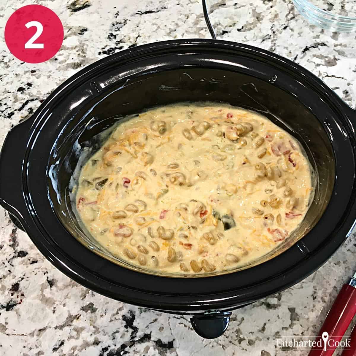 Macaroni and shredded cheddar cheese are stirred into the macaroni and cheese sauce ingredients in a large slow cooker.