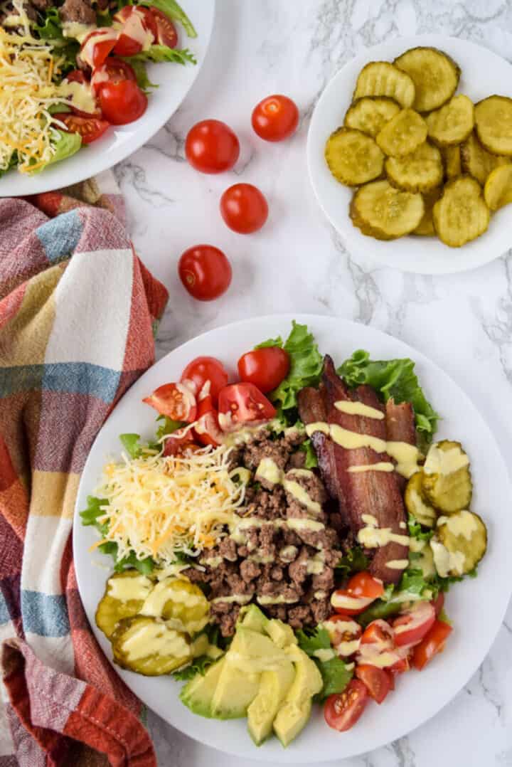 Ground beef and bacon cheeseburger salad on a white plate.