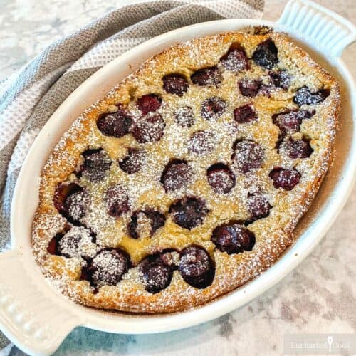 Baked cherry clafoutis in a white baking dish.
