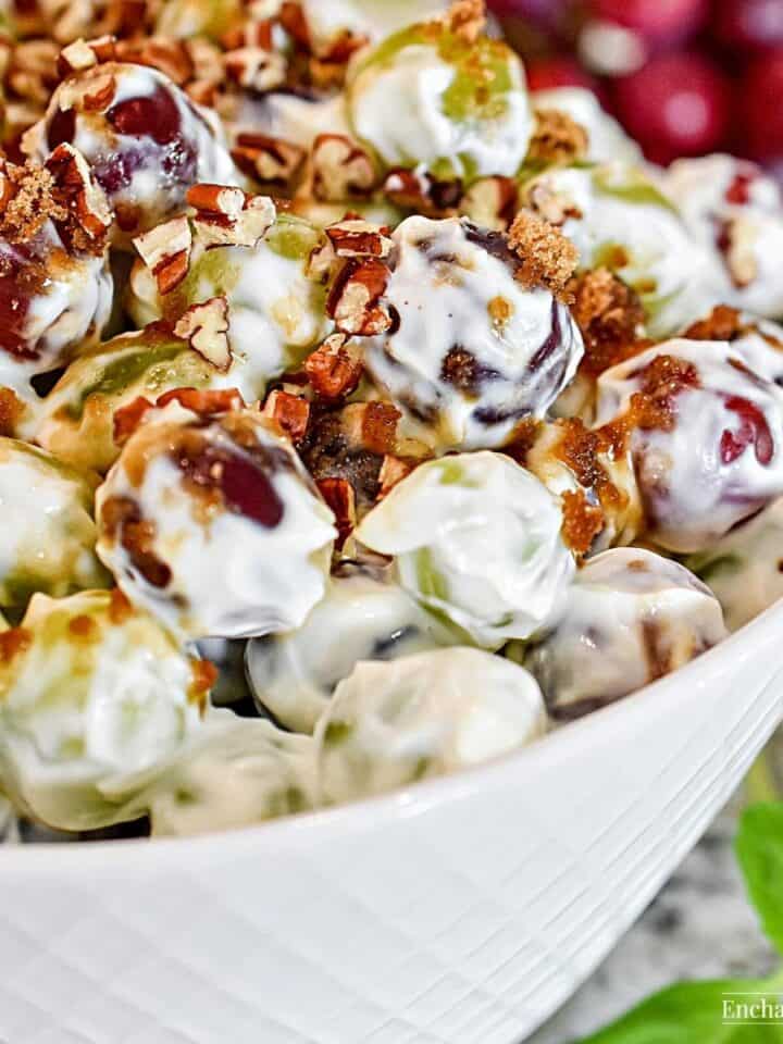 Grape salad topped with brown sugar and pecans in a large white bowl.