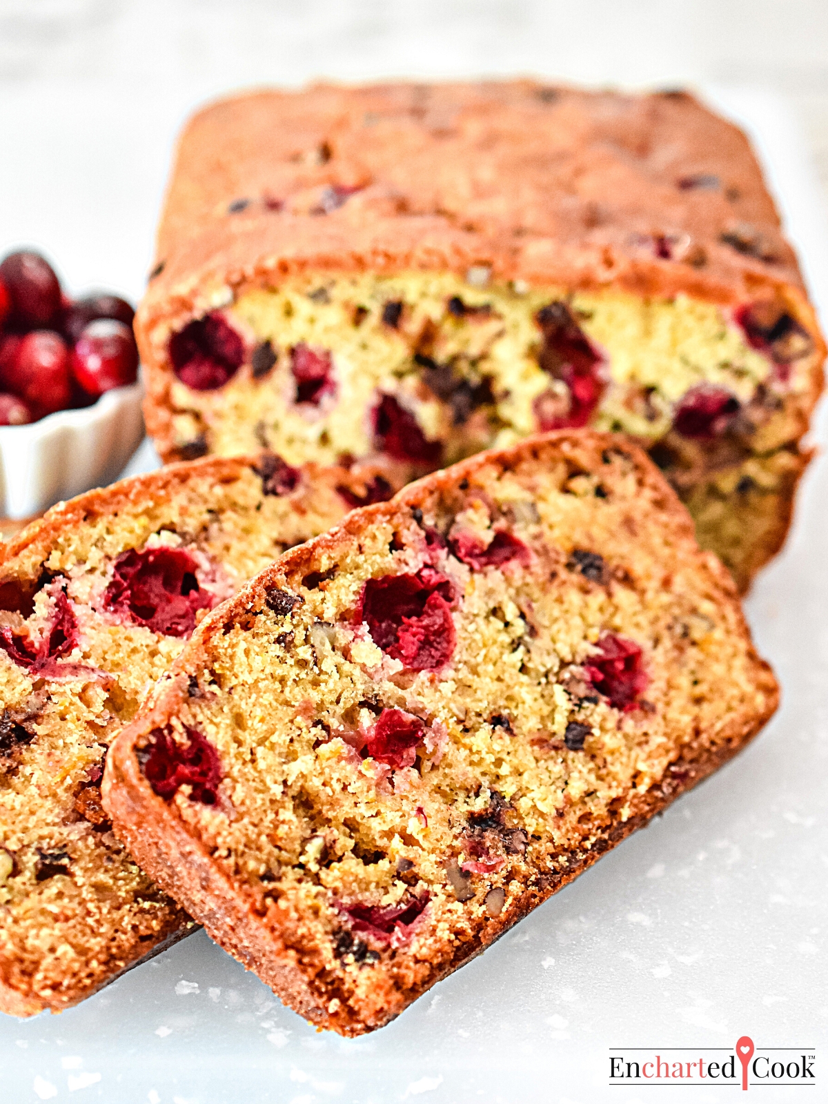 Cranberry Bread sliced on a white cutting board.