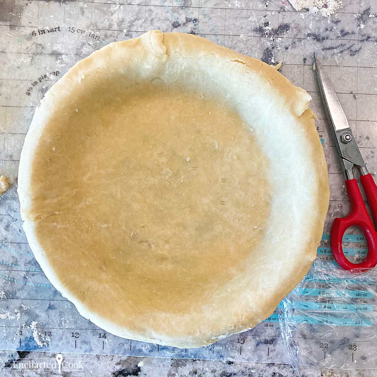 Trimming the pie crust in the pan with scissors.