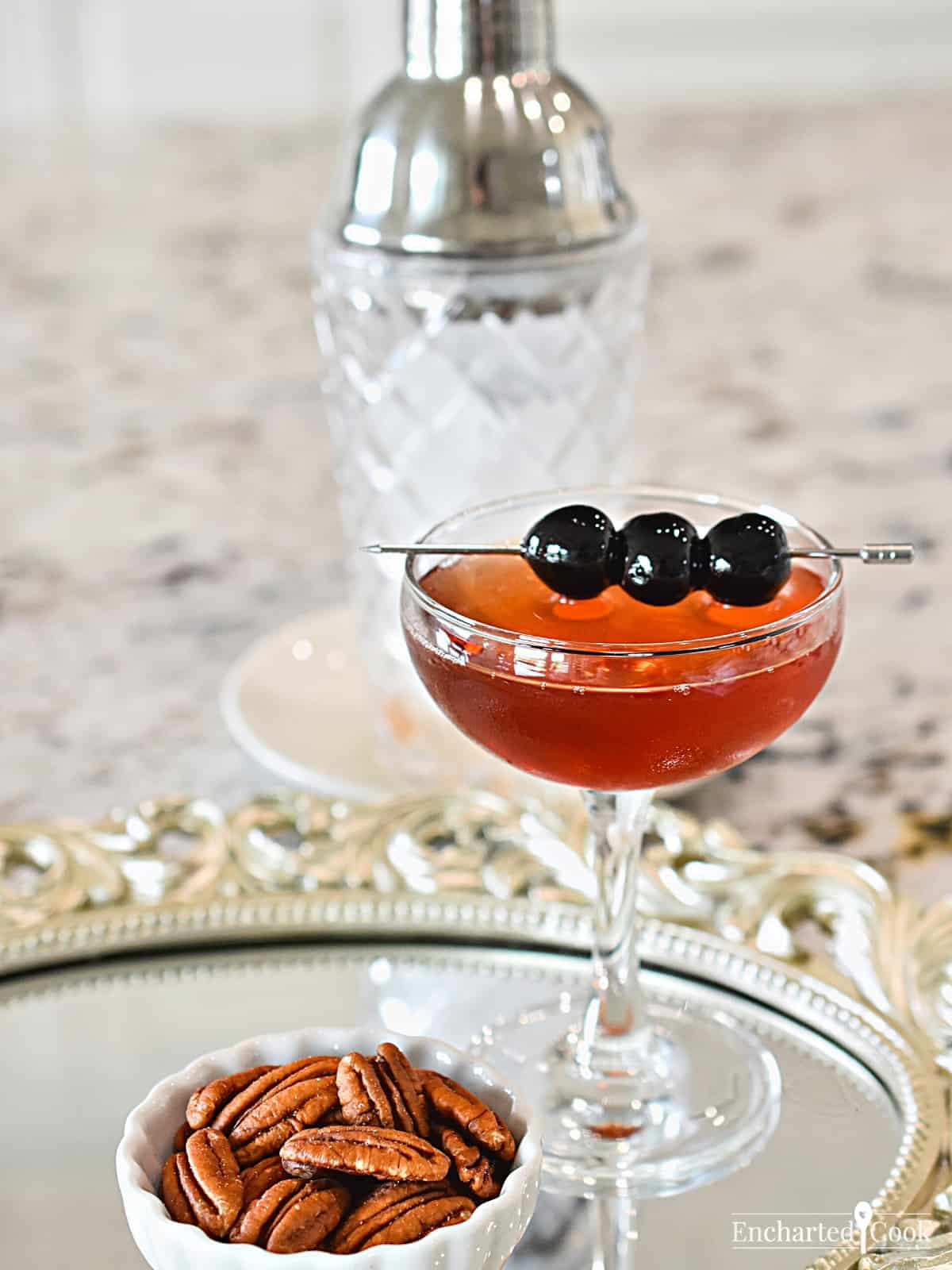 The cocktail in a coupe glass garnished with cocktail cherries.