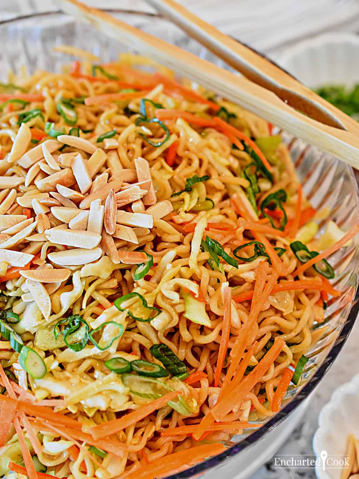 Close up view of the salad in a large clear bowl with chop sticks.