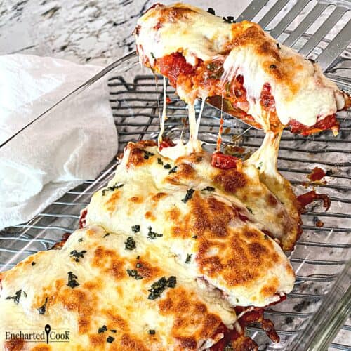 Cheesy Chicken Tenders Parmesan are smothered in marinara sauce and cheese in a glass baking dish.