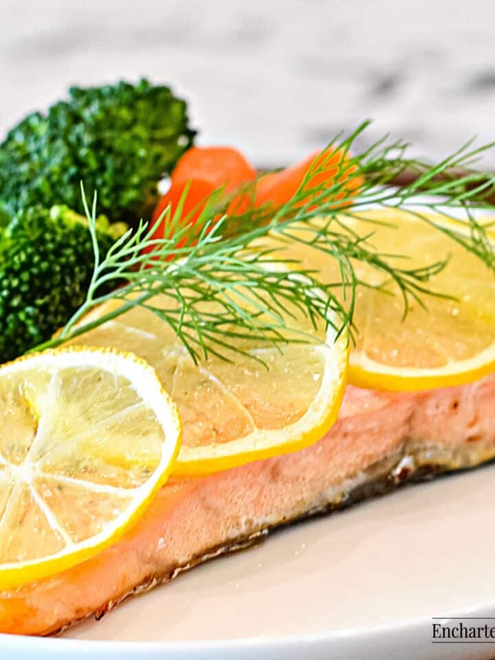 A fillet of Atlantic salmon with its skin on, cooked in butter and lemon on a white plate.