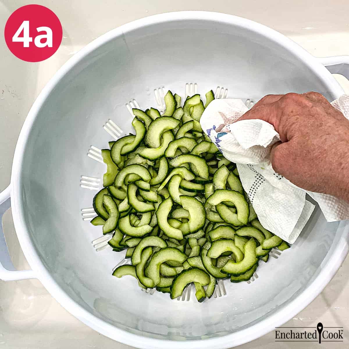 Process Photo 4a - The brined slices of cucumber are drained an blotted in a large white colander.