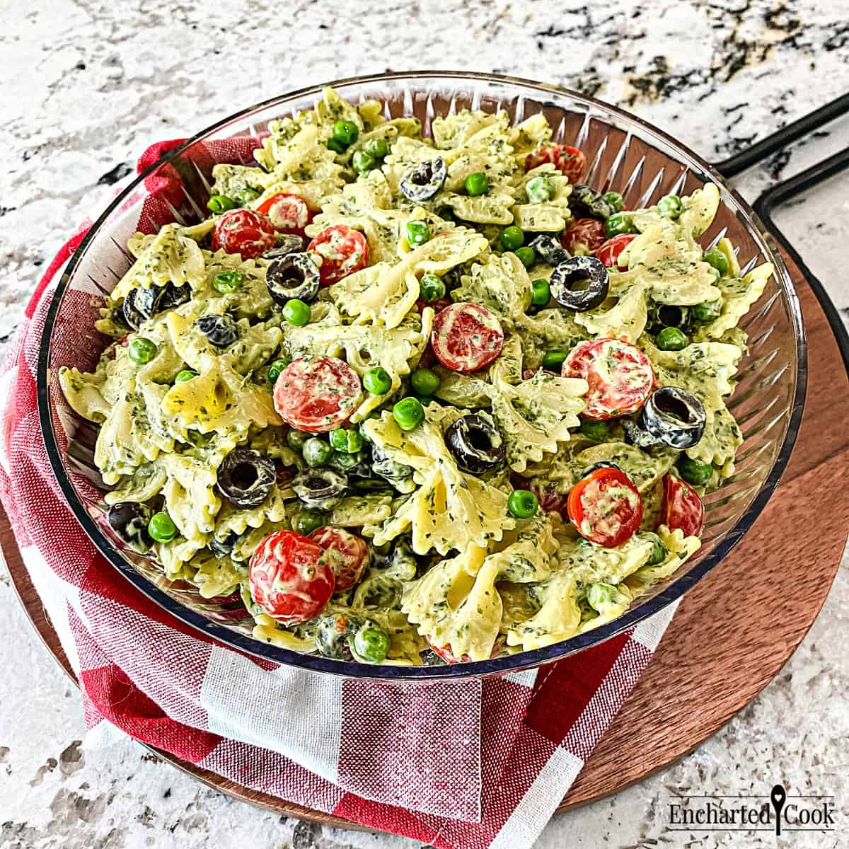 Green Goddess Pasta Salad made with bow tie pasta in a clear bowl with a red and white checked napkin.