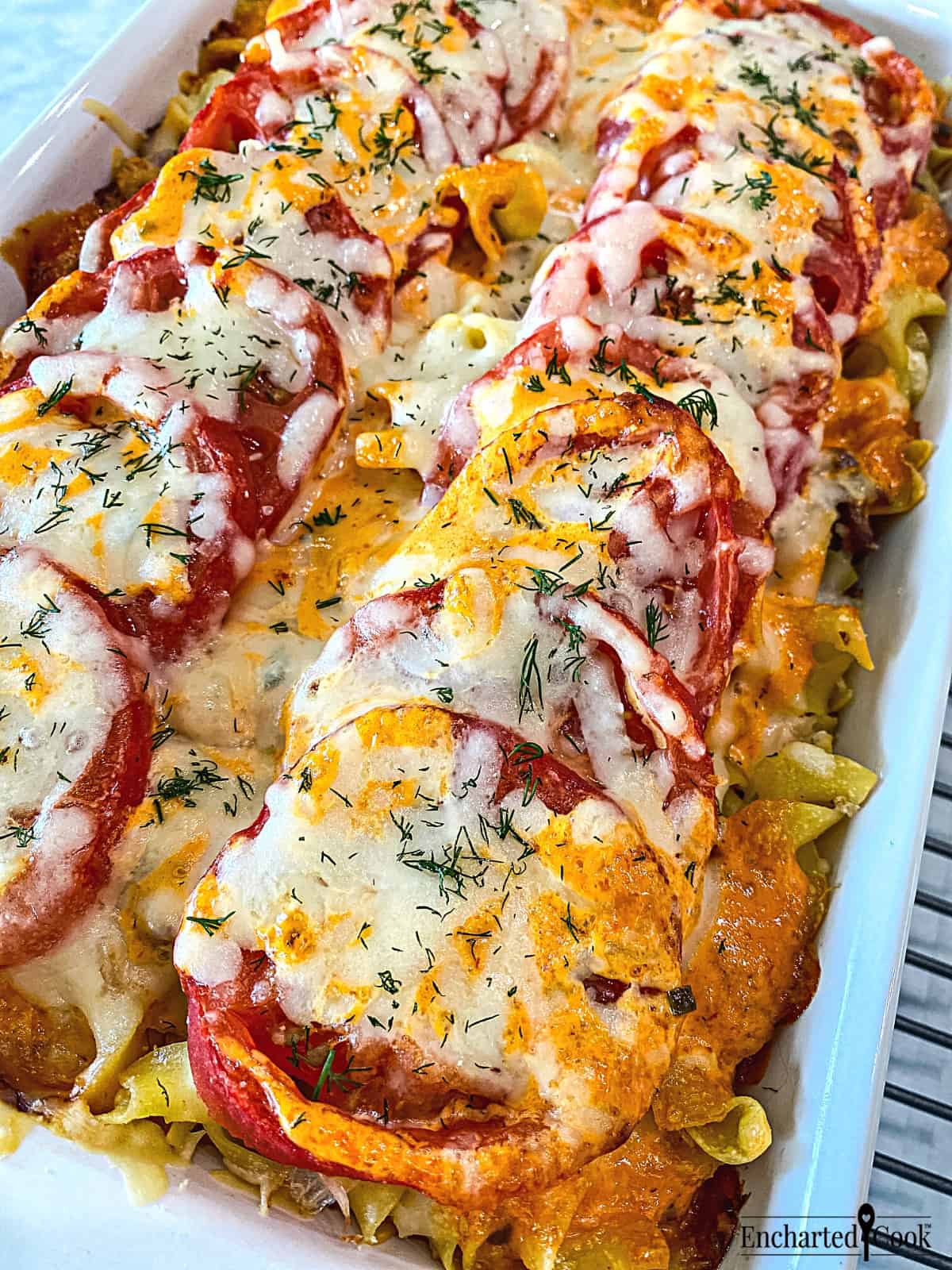 Reuben casserole topped with tomato, cheese, and thousand island dressing fresh from the oven.