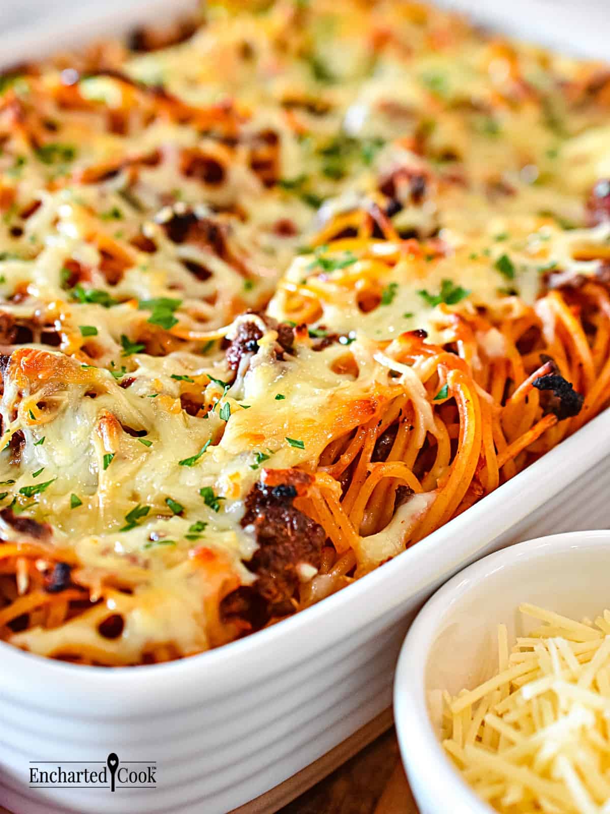 Spaghetti with marinara sauce topped with cheese in a white baking dish.