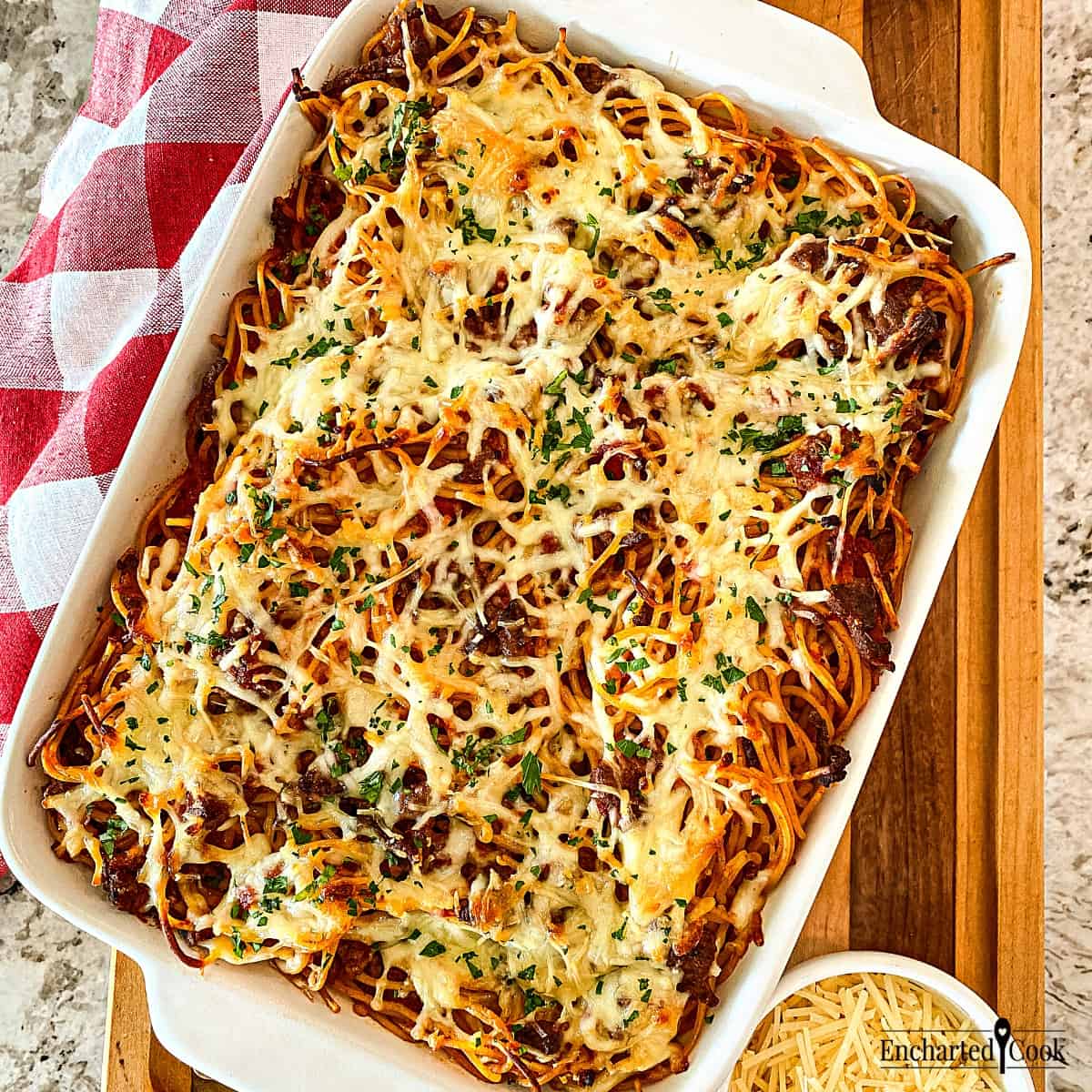 Spaghetti with marinara sauce topped with cheese in a white baking dish.