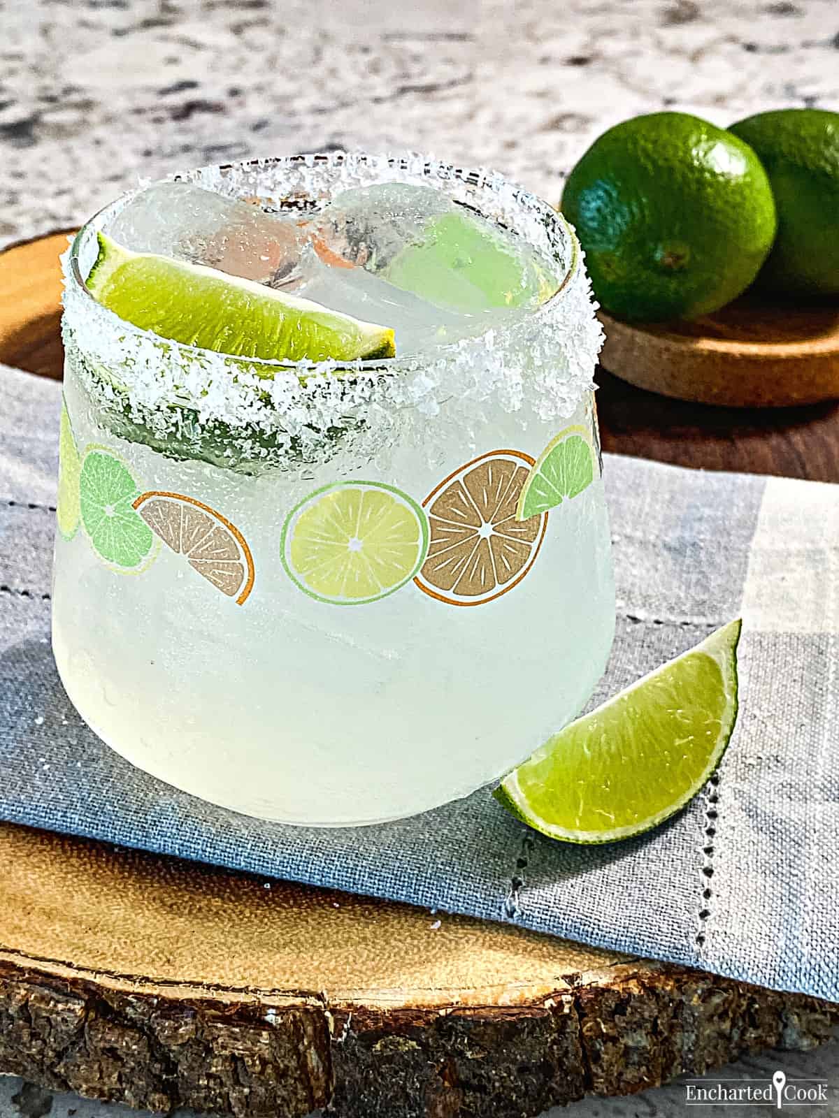 A classic margarita over ice in a salt-rimmed glass with a wedge of lime.