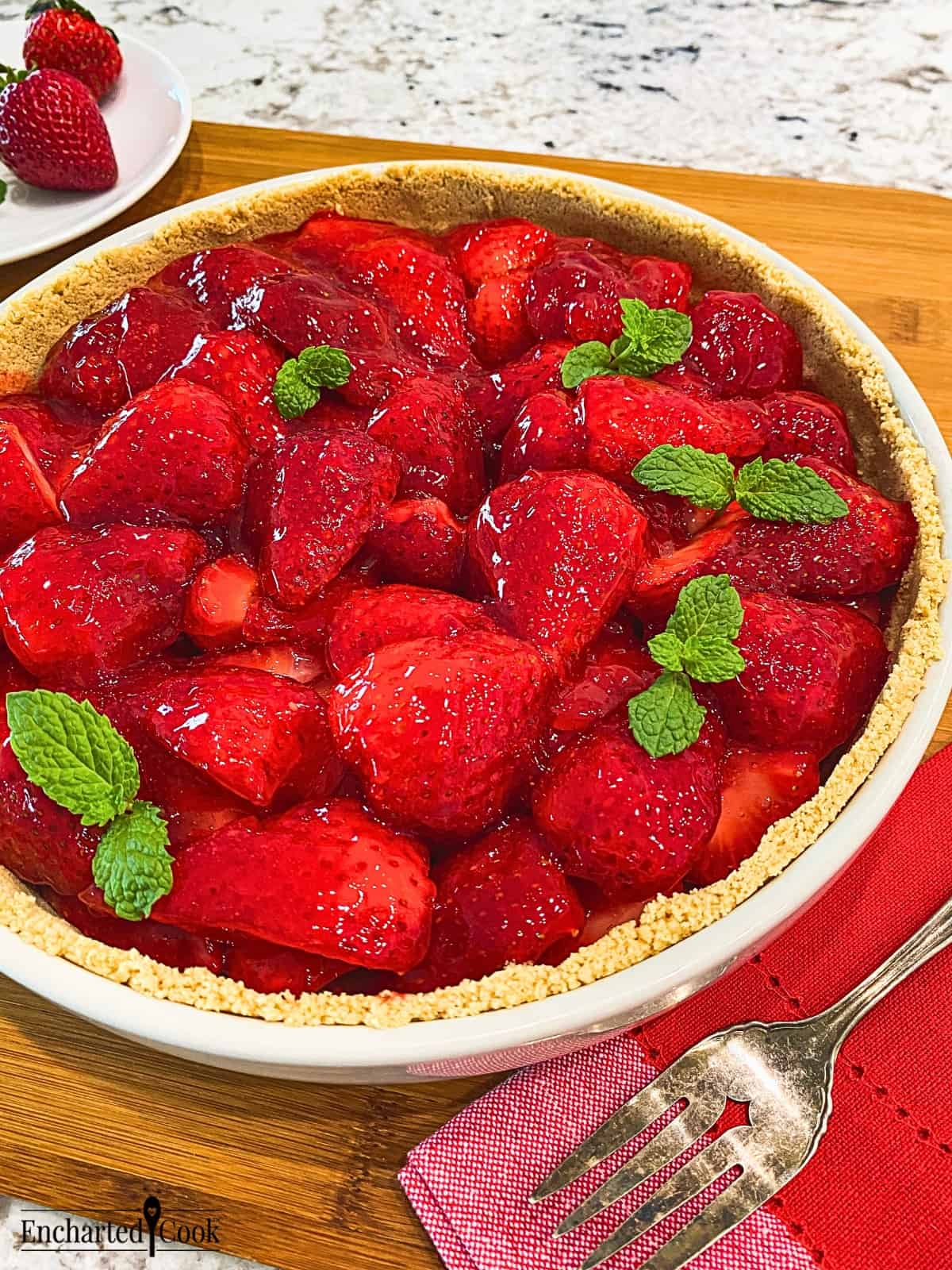 A whole strawberry pie garnished with fresh mint.
