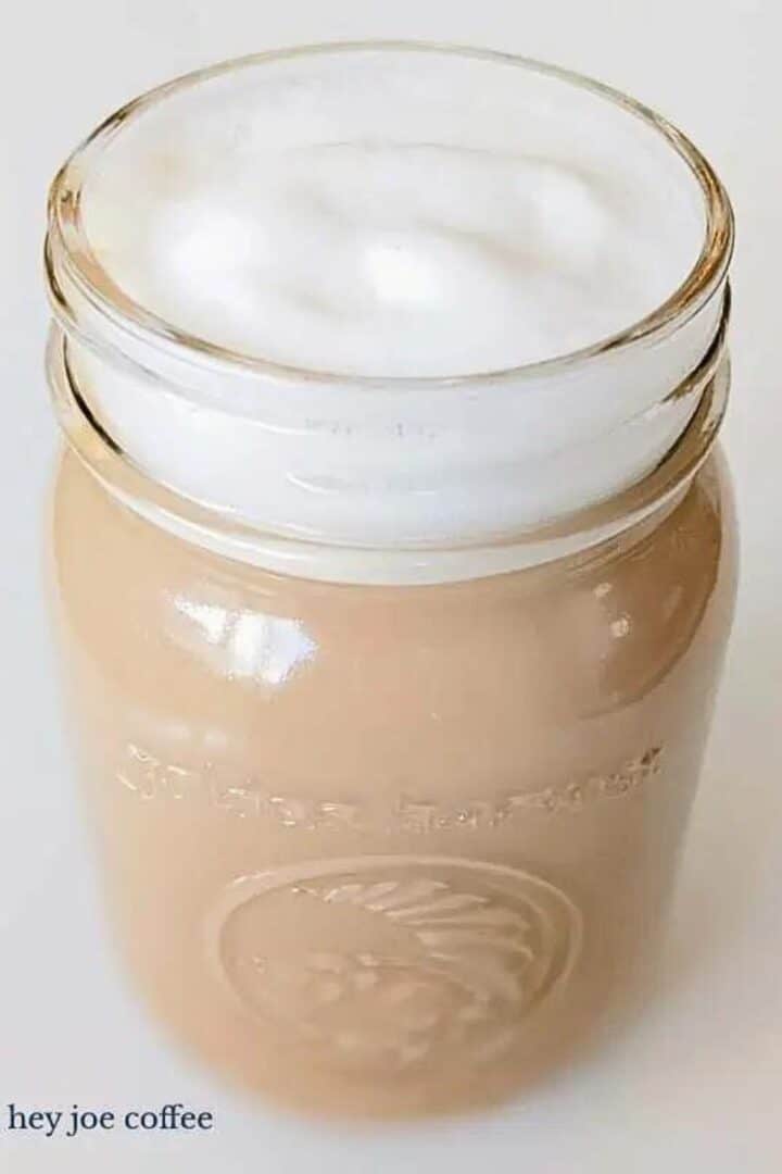 A creamy vanilla latte with foam in a canning jar.