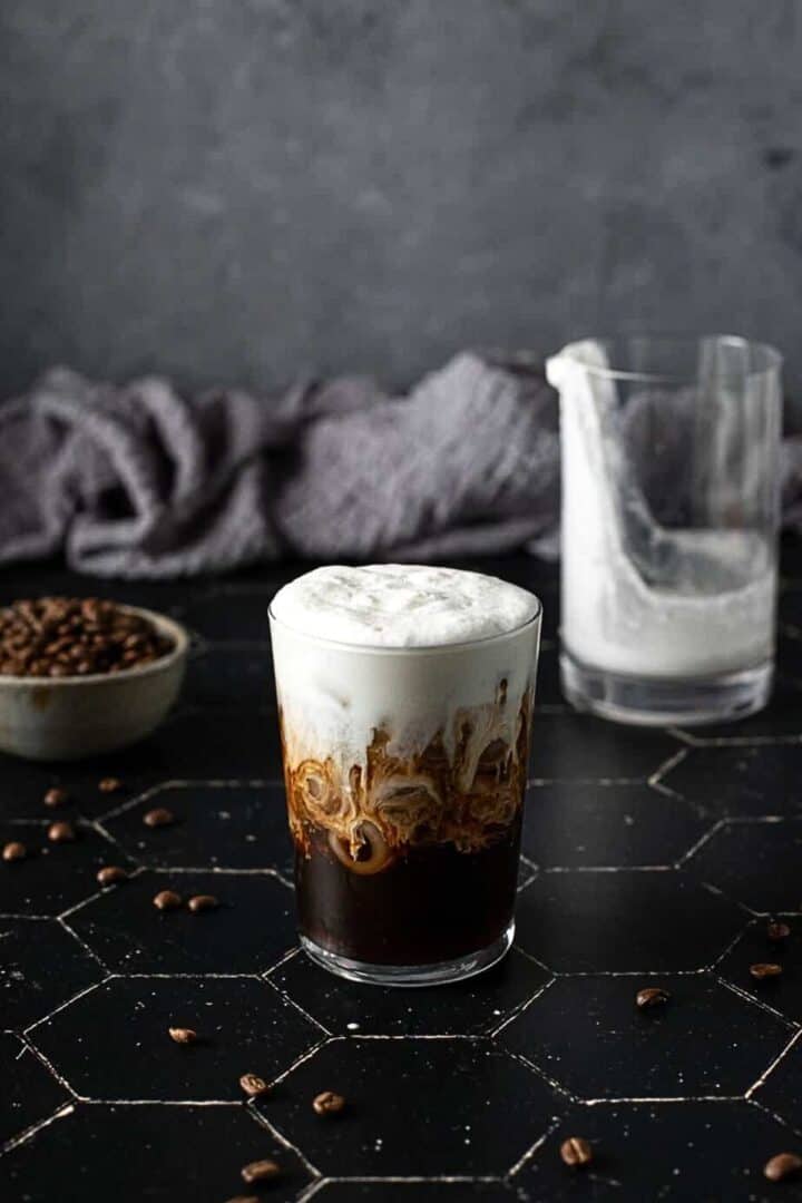 A dark iced coffee with thick creamy cold foam.
