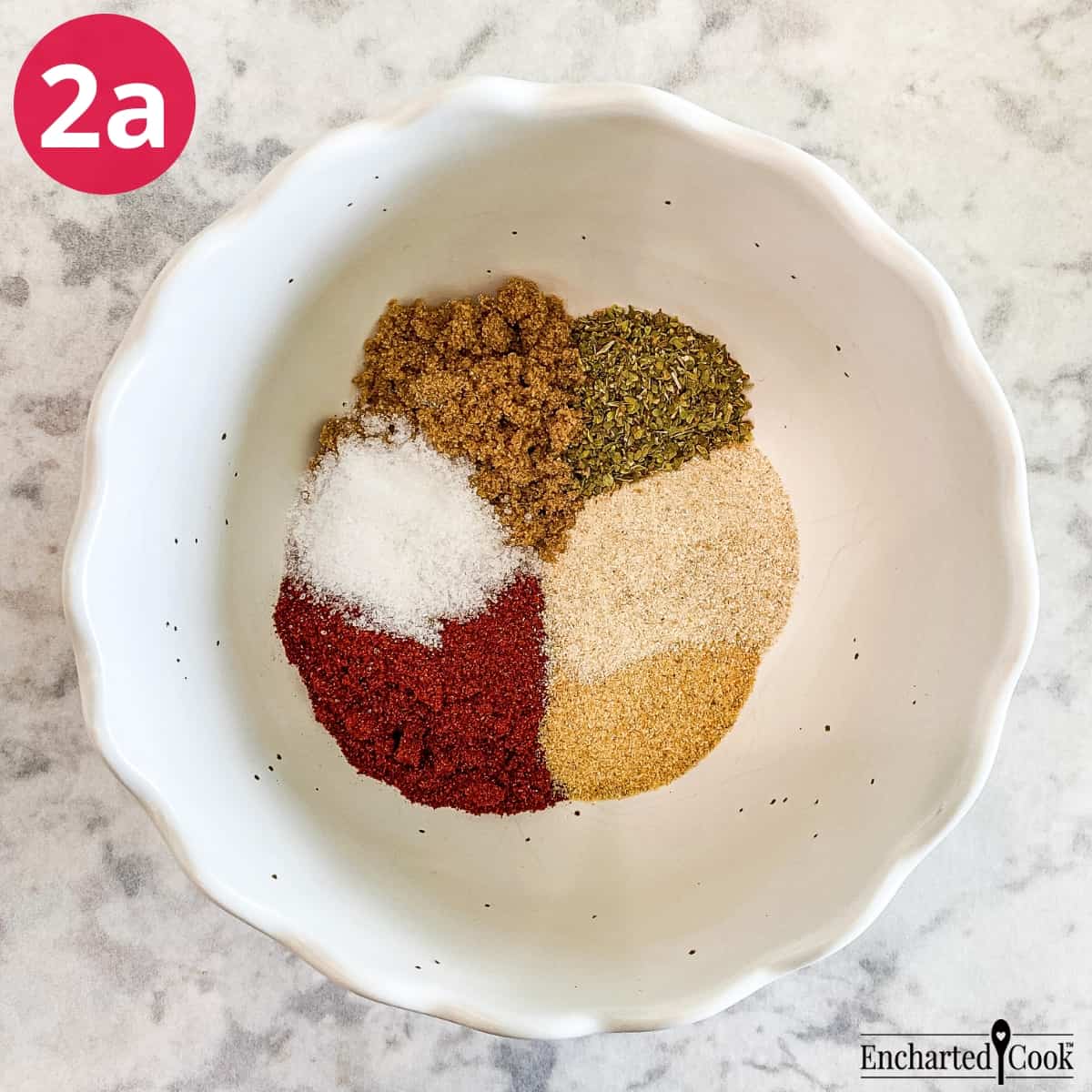 Process Photo 2a - A small bowl contains paprika, salt, dark brown sugar, oregano, onion powder, and garlic powder to make a spice rub for the chicken.