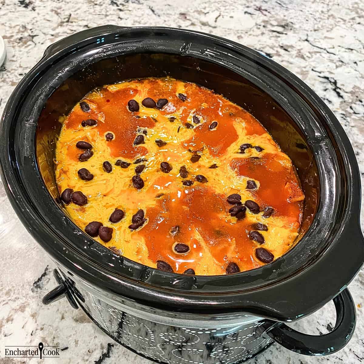 The cheddar cheese is completely melted and the enchilada casserole is fully cooked in the crock pot.