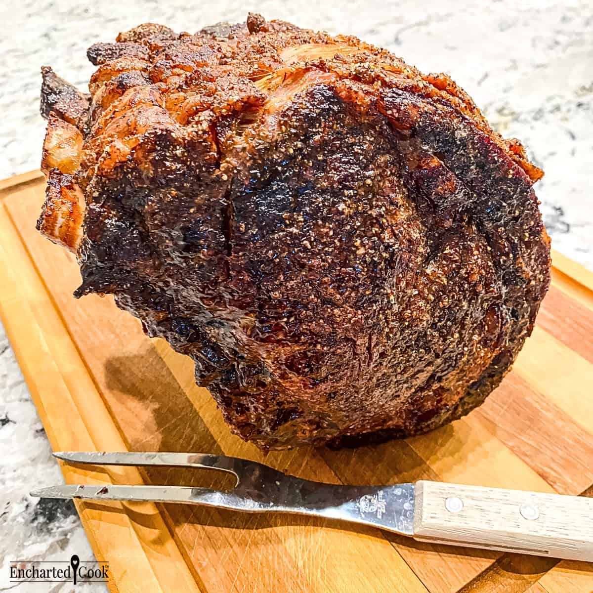 A beautifully cooked standing rib roast standing on end on a wooden carving board.