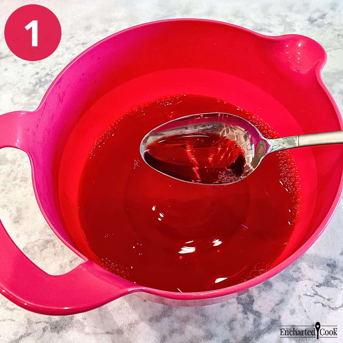 Process Photo 1 - The raspberry Jello is fully dissolved in boiling water in a large pink mixing bowl.