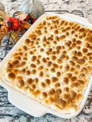 A fully baked sweet potato casserole with a layer of melted and toasted miniature marshmallows on top is ready to be served and enjoyed.