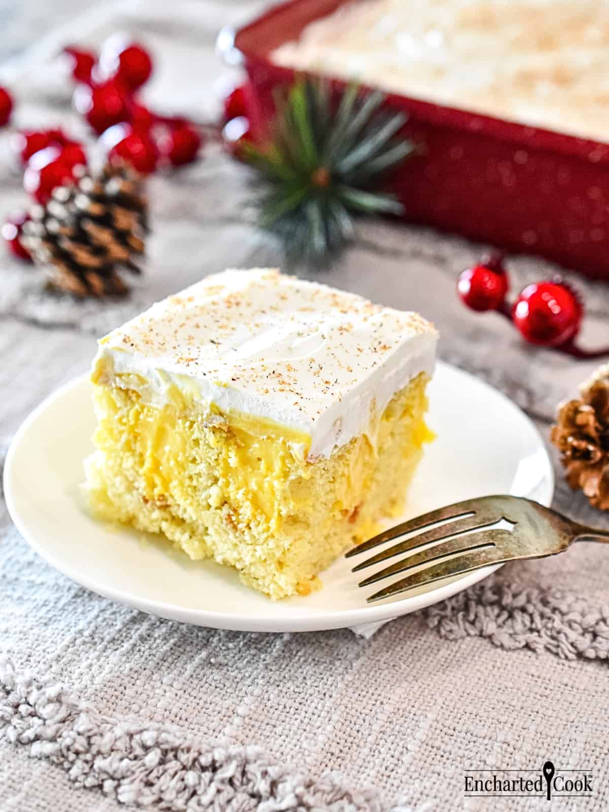 A slice of yellow eggnog cake on a white plate with a fork.