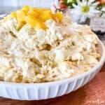 Fluff dessert in a white bowl topped with pineapple.